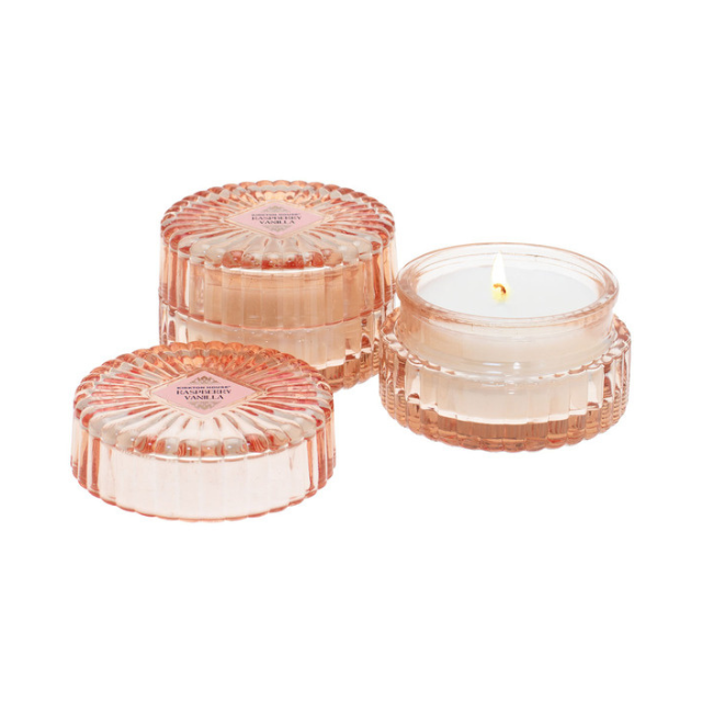 Three clear textured containers one with a lit candle inside and two with lids on