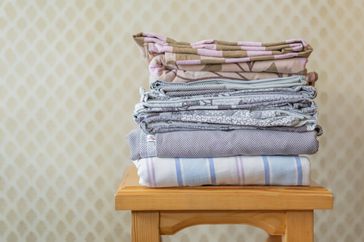 stack of textile sheets blankets on a wooden shelf