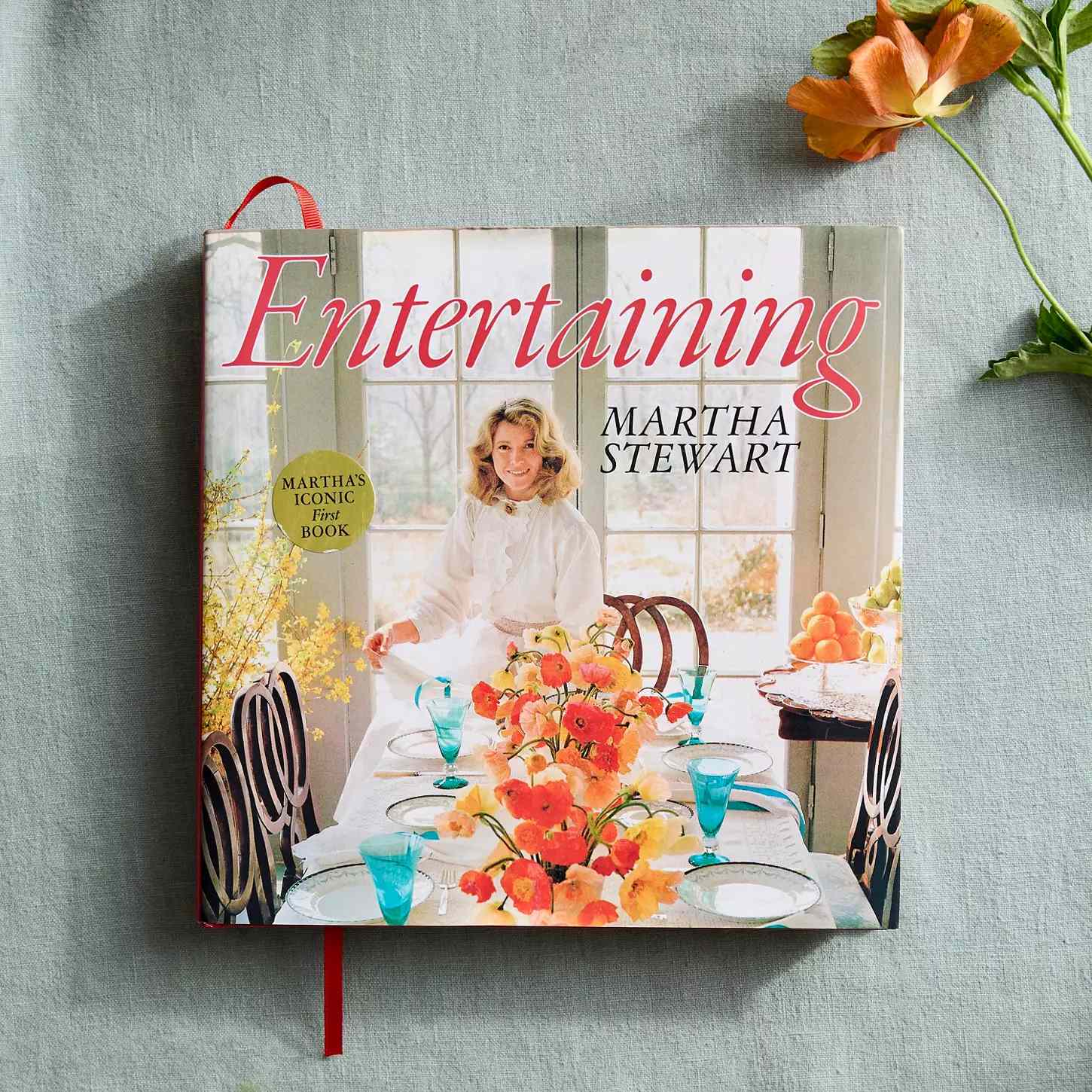 The book Entertaining by decorvow placed on a surface with a flower nearby