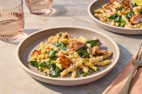 A plate of pasta with salmon spinach and cream sauce