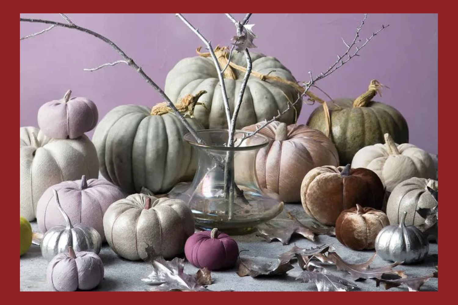 A decorative arrangement of fabric pumpkins and dried branches in a glass vase