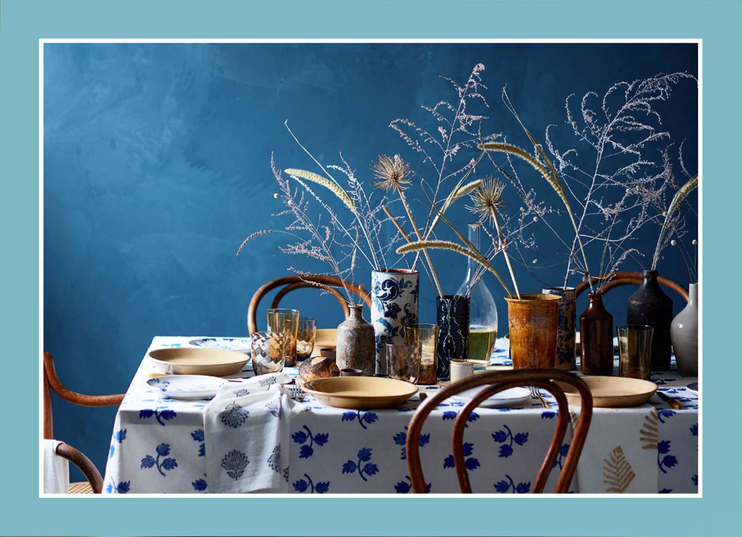 blue table with dishes with blue background dried flowers