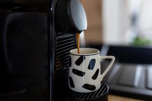 A coffee machine brewing coffee into a patterned mug
