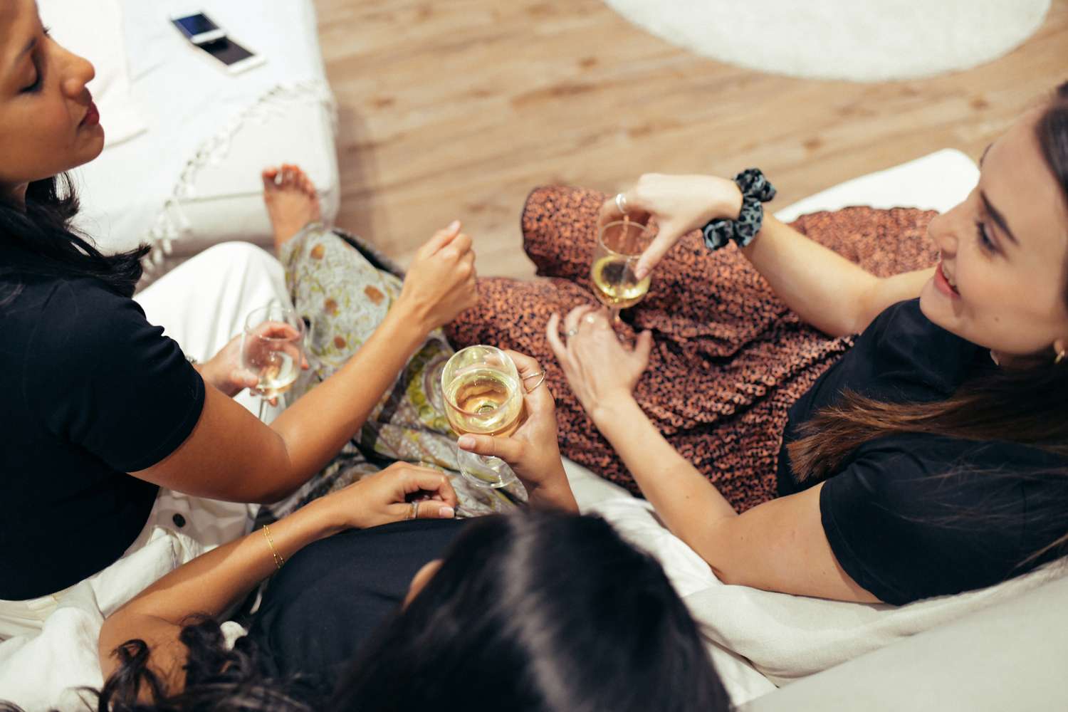 A group of people sitting on a sofa holding glasses engaged in conversation
