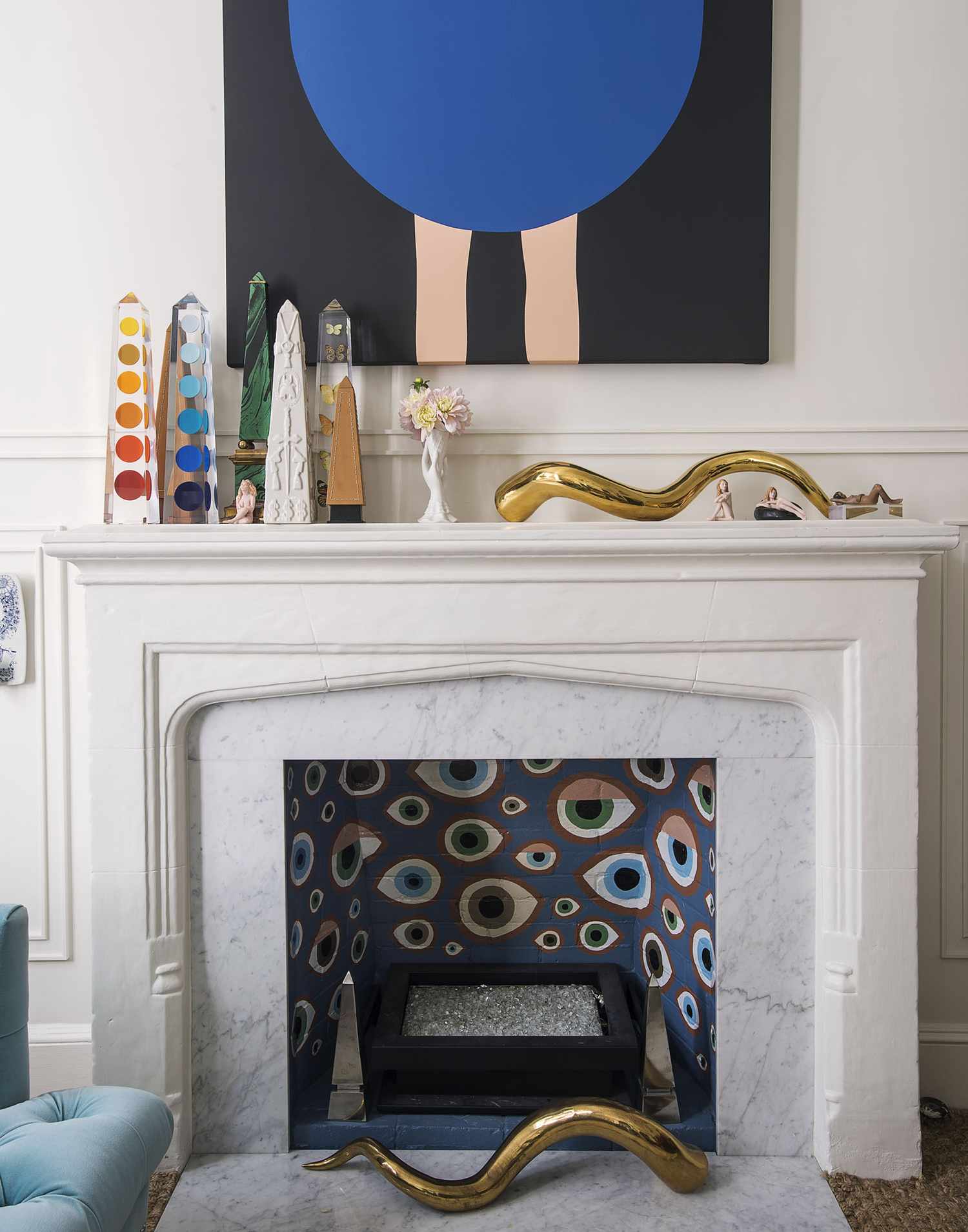 A decorated fireplace in a living room with art and ornaments displayed
