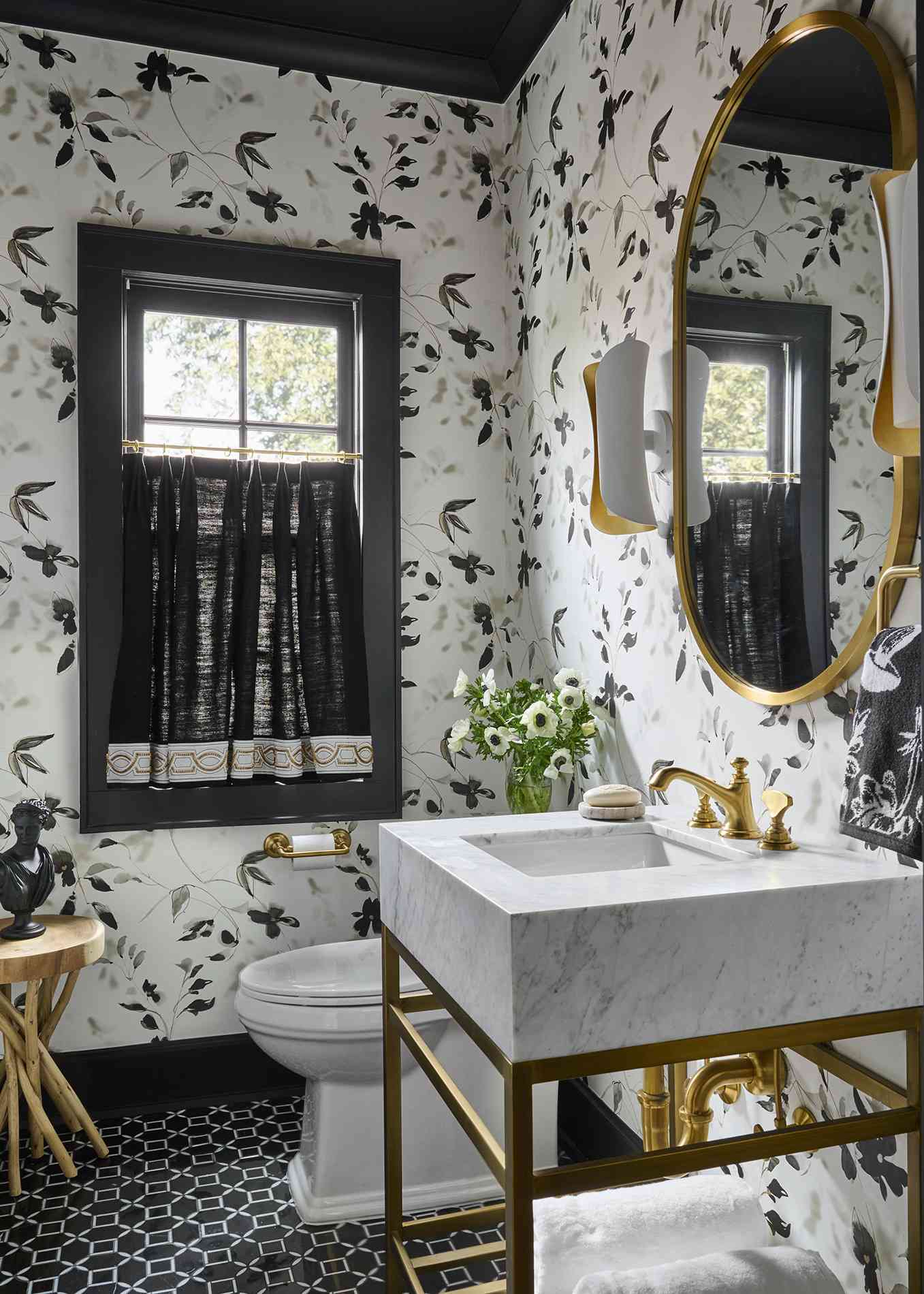 powder bathroom with black and white floral wallpaper and brass accents