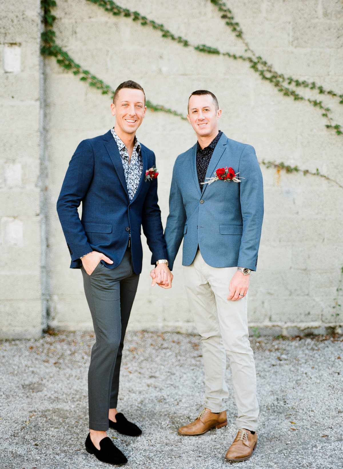 grooms wearing blue gray accented wedding suits with red boutonnieres