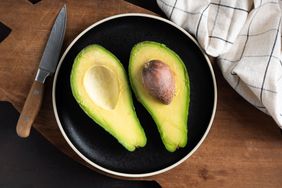 Avocado cut in halves on plate, top view. Tropical fruit rich in omega 3 fatty acids. Healthy food