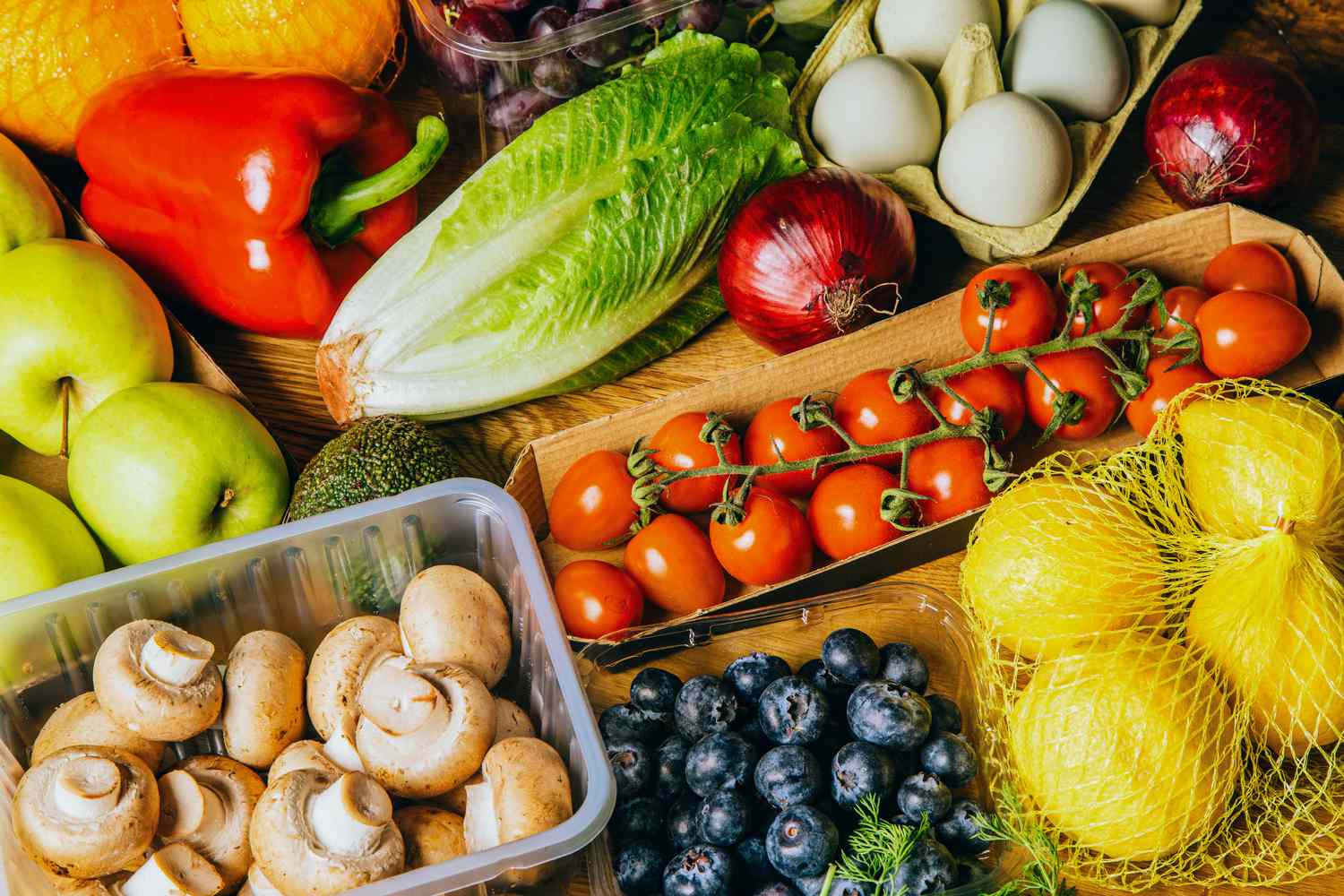 selection of fresh fruits and vegetables including cherry tomatoes, mushrooms, and blueberries, on wooden table