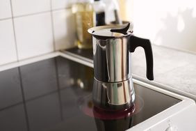 Metal stovetop espresso maker with a black handle on an induction stove