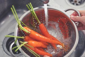 Carrots being rinsed in a colander under running water