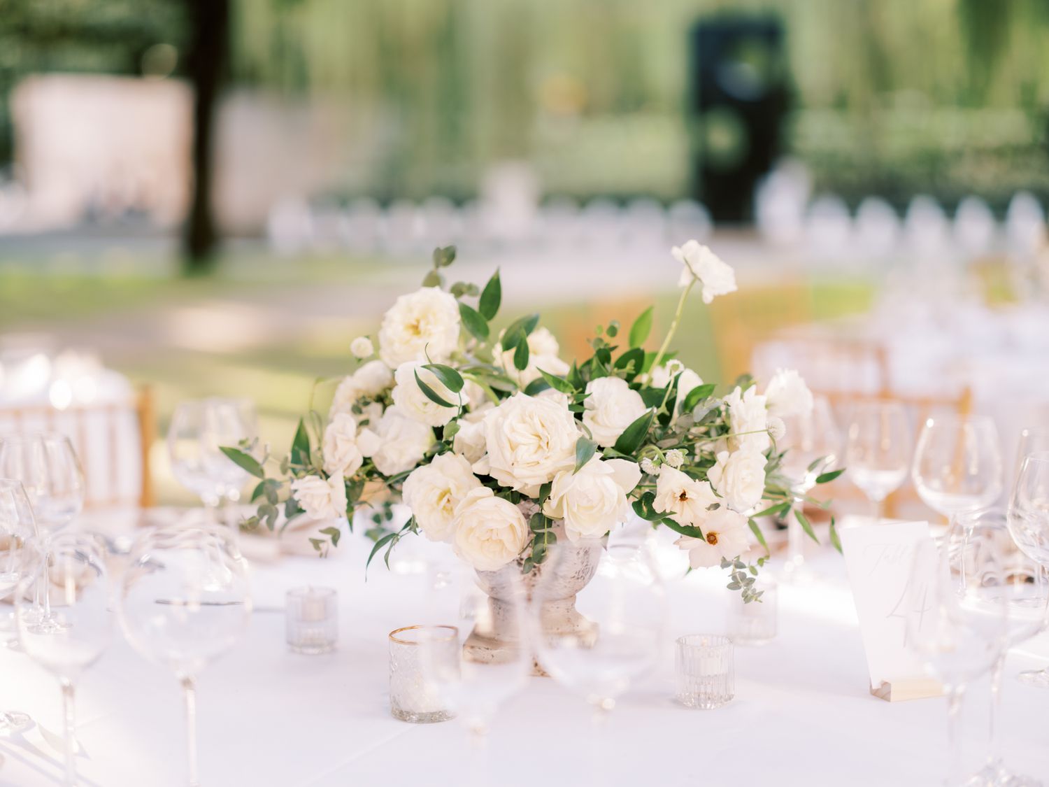 reception table with white floral centerpiece and stemmed glassware