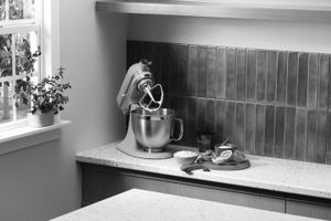Kitchen counter with a stand mixer ingredients and fruit arranged near a cutting board