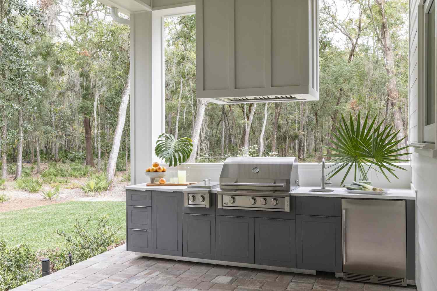 a gray outdoor kitchen that juts out into a backyard in one line