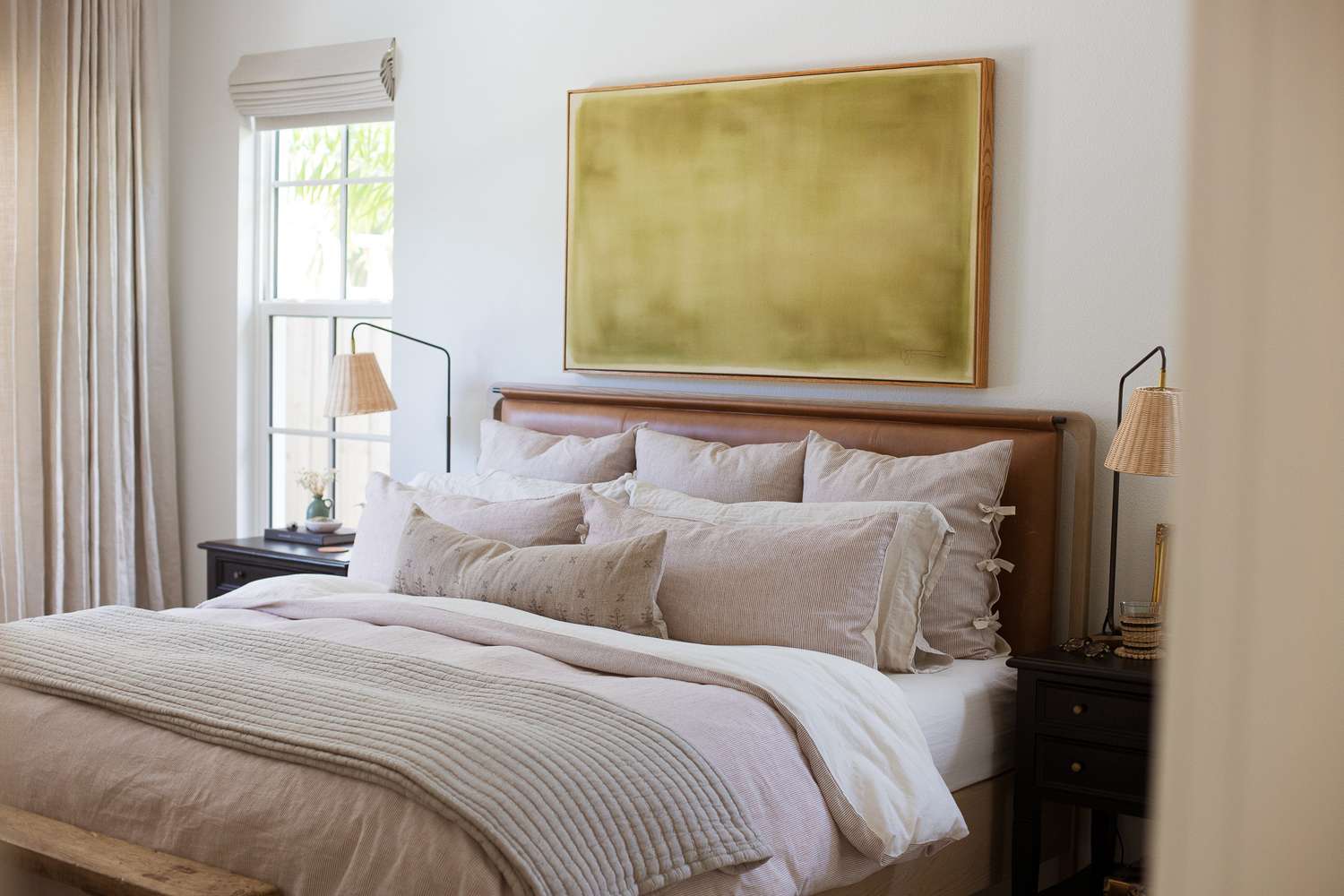 A neatly arranged bedroom with a large bed and artwork hung on the wall