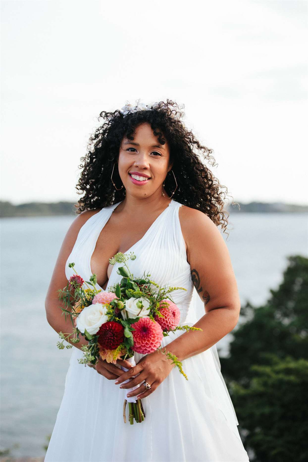 bride by water holding pink tones wedding bouquet