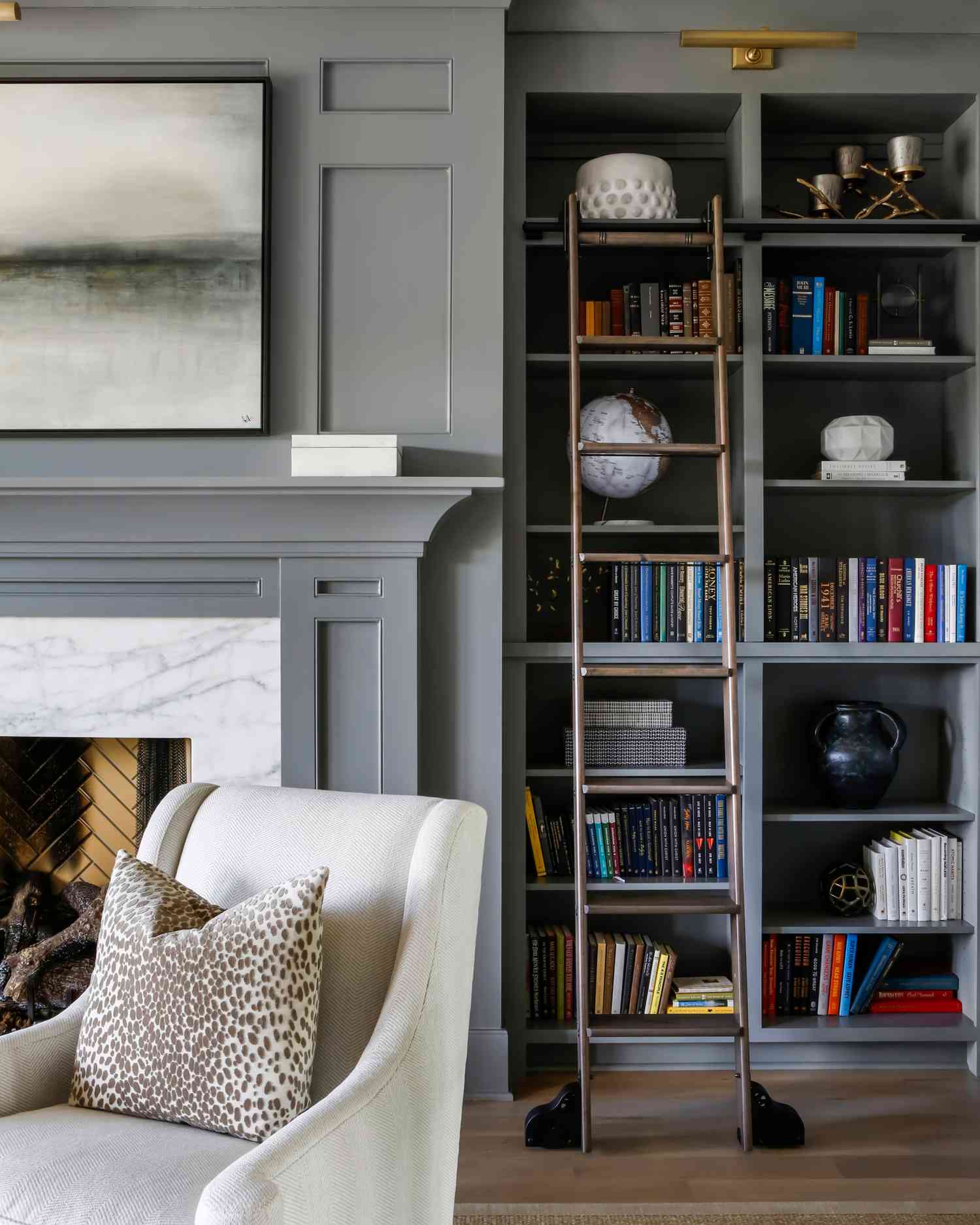 Grey home library with ladder and fireplace area