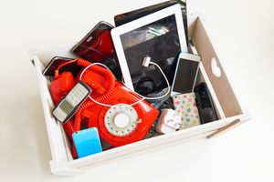 A box containing assorted electronic and phone devices including retro and modern styles
