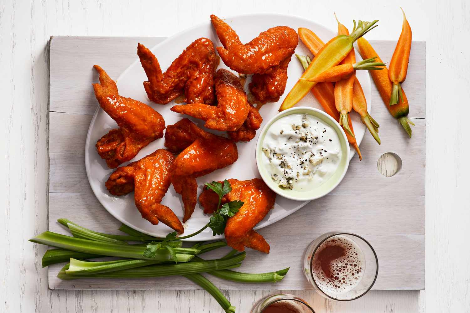 A plate of buffalo wings with a side of blue cheese dip celery sticks and carrots