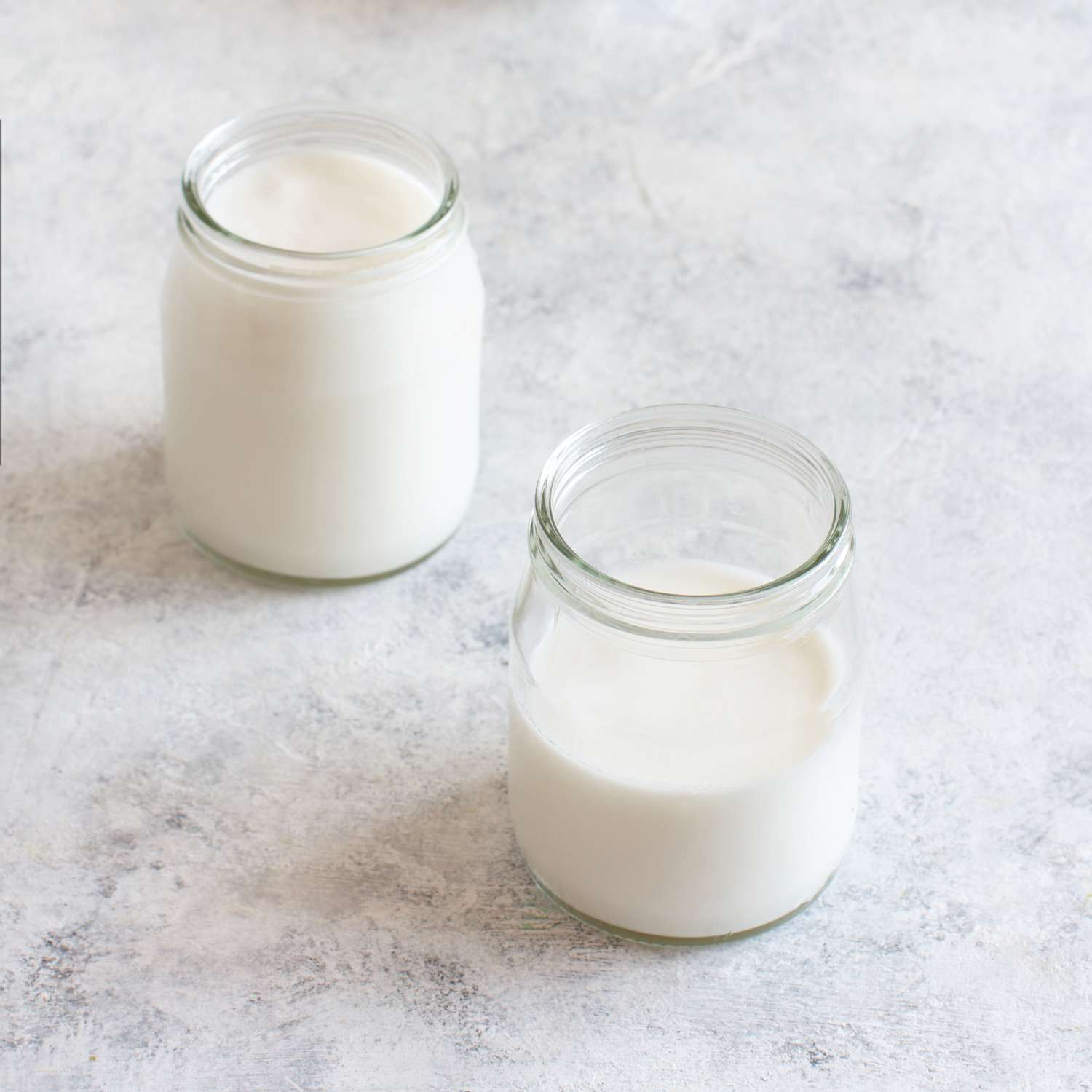 kefir in 2 glass jars on pale surface