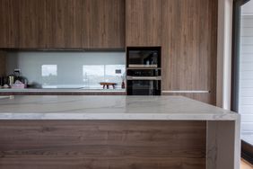 Modern kitchen with a marble countertop woodpanel cabinets and builtin appliances