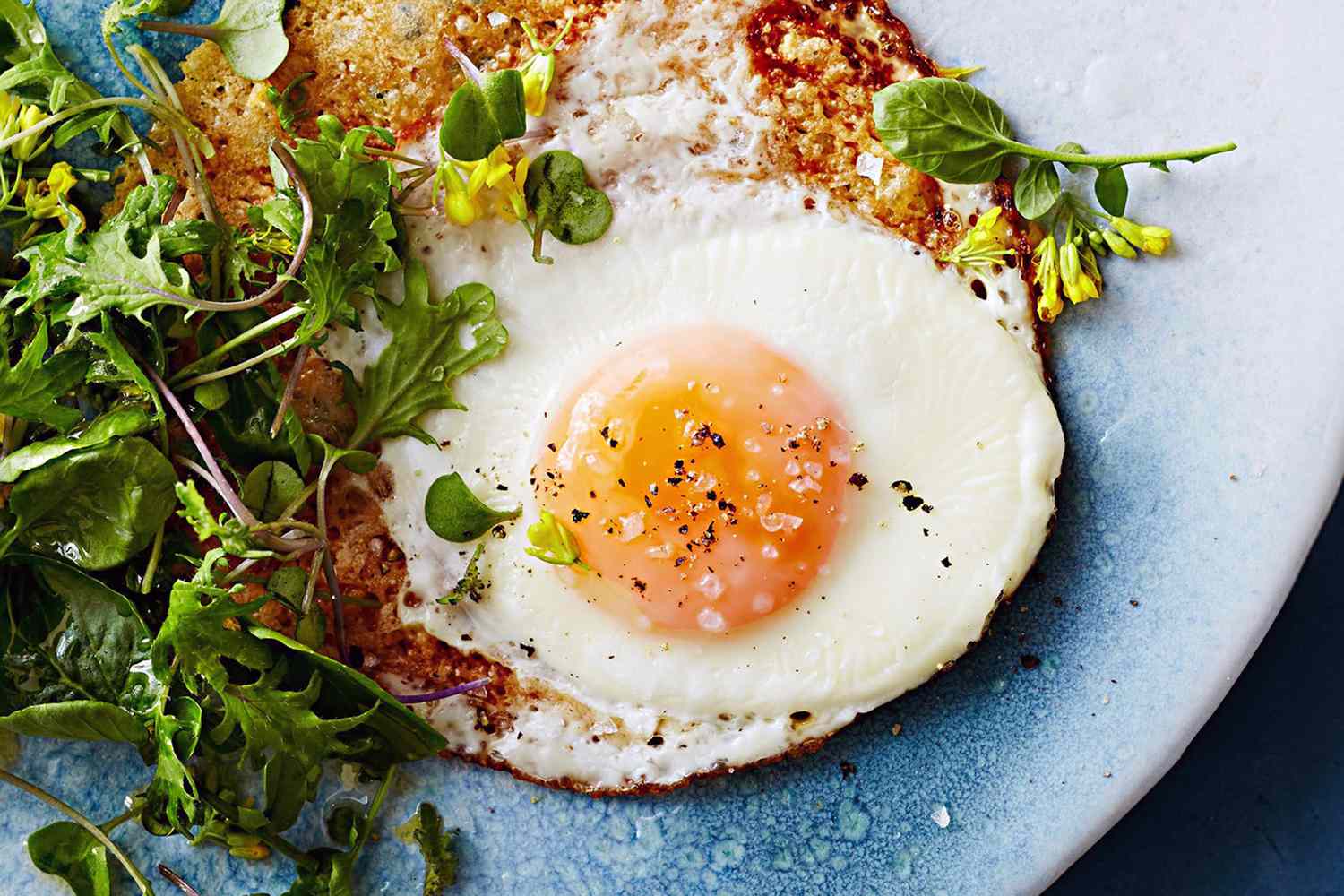 Egg cooked sunny side up served with fresh greens on a plate