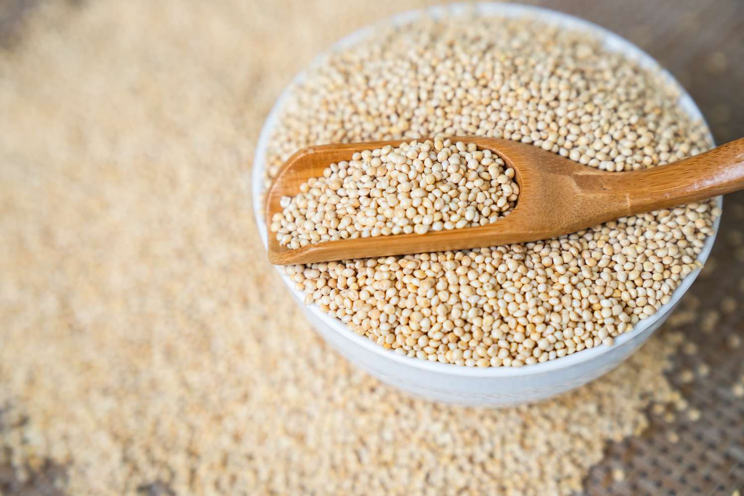 Millet in spoon above bowl