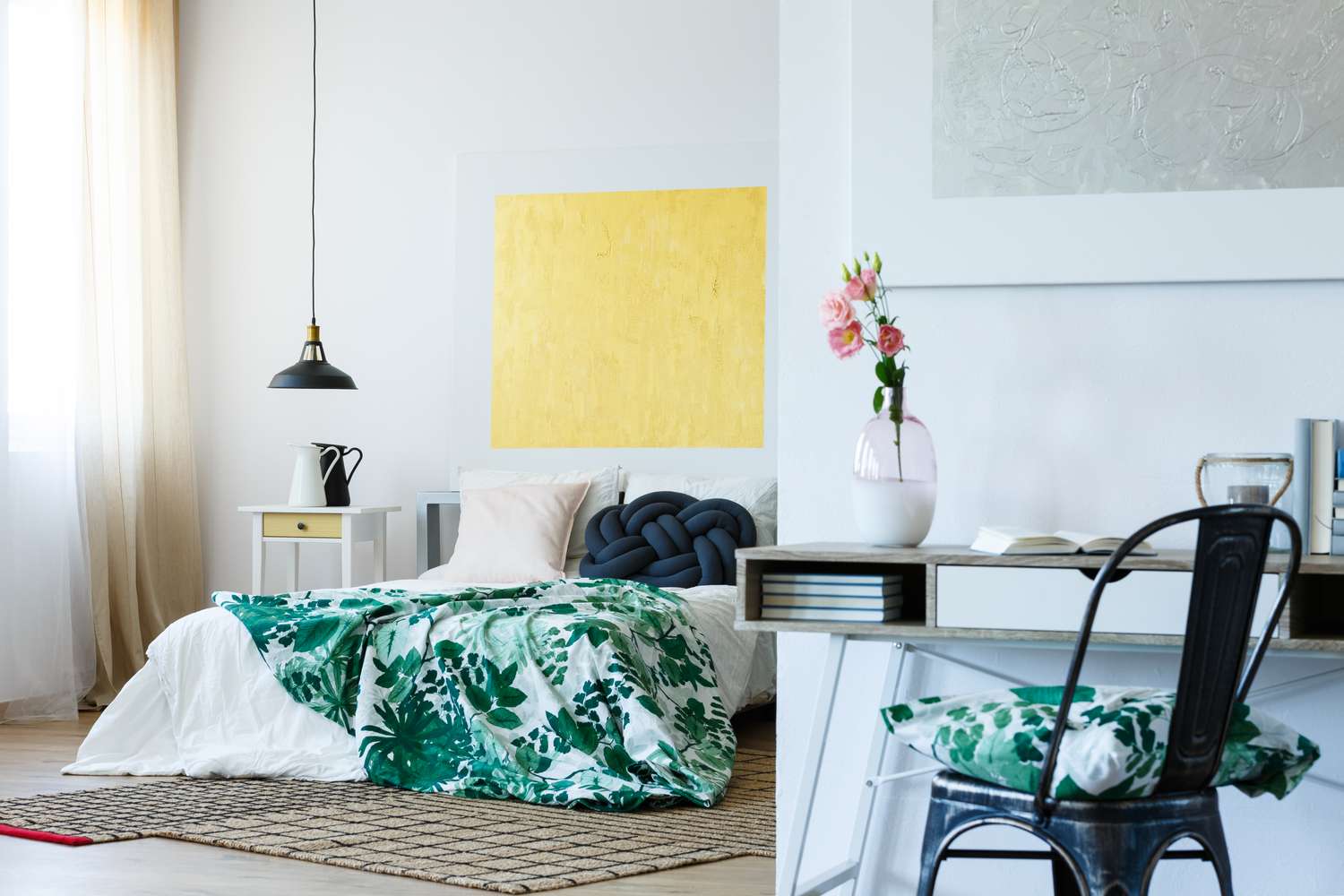 A modern cozy bedroom setting with a patterned bedspread desk chair and decorative accents