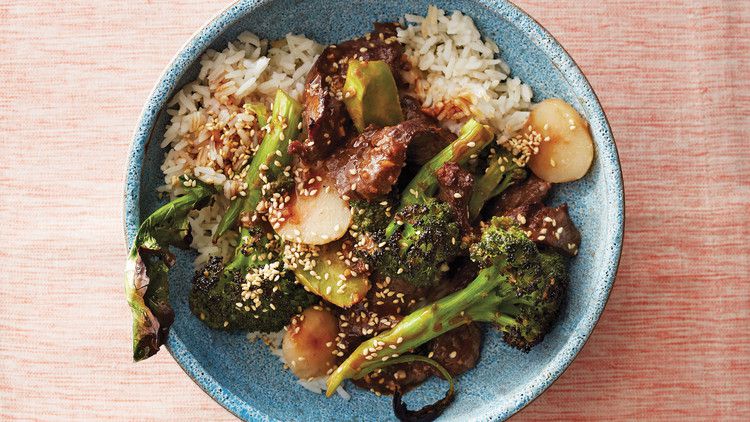 beef stir-fry with broccoli and water chestnuts in blue bowl atop pink table cloth
