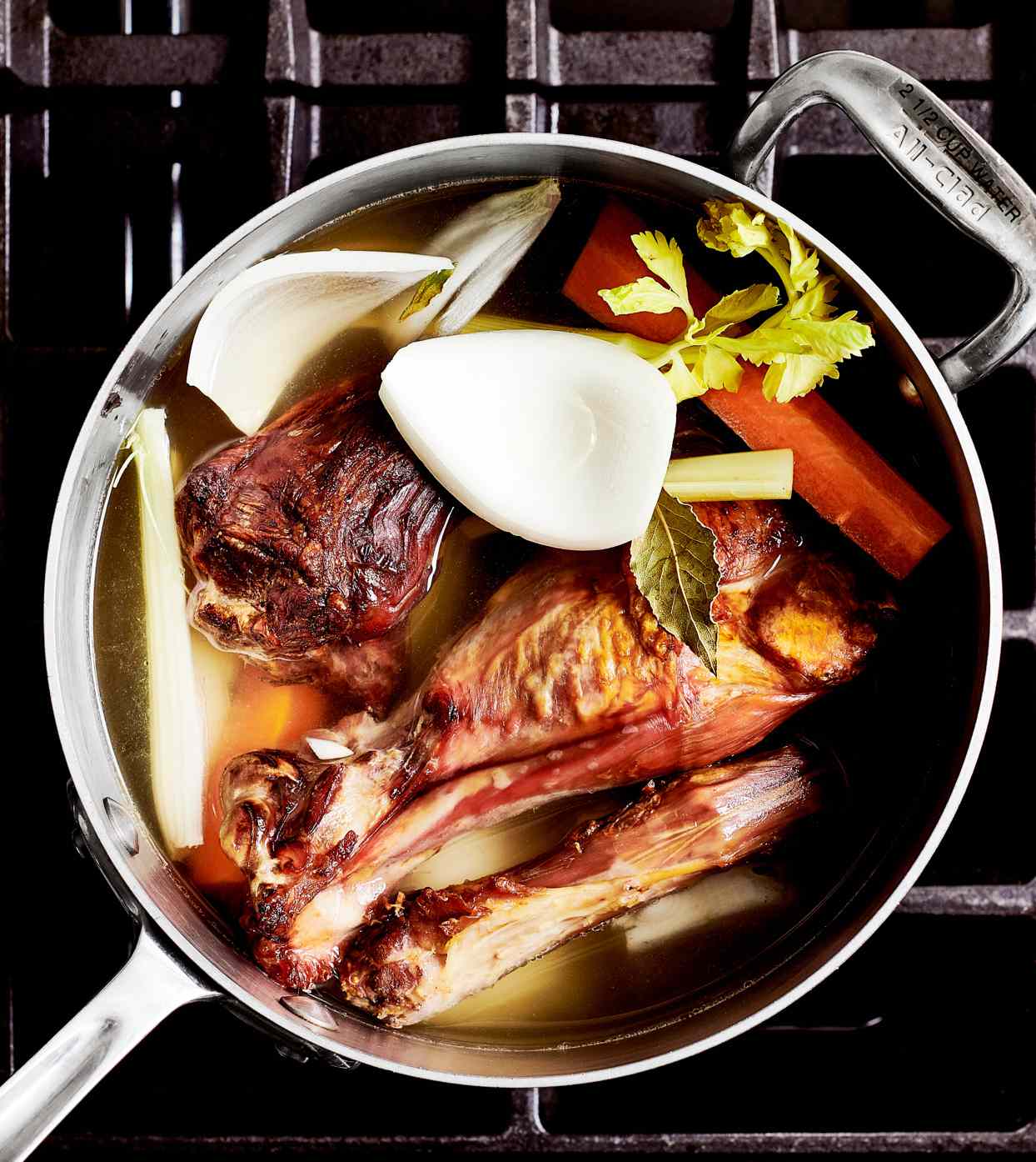 turkey parts and vegetables simmering in roasting pan