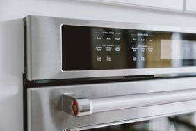 Control panel and handle of a modern stainless steel oven displaying cooking options and settings