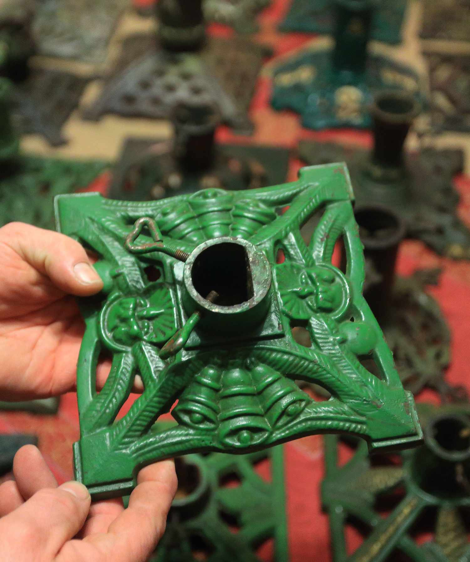 Person holding an ornate base likely part of a stand or structure surrounded by similar components