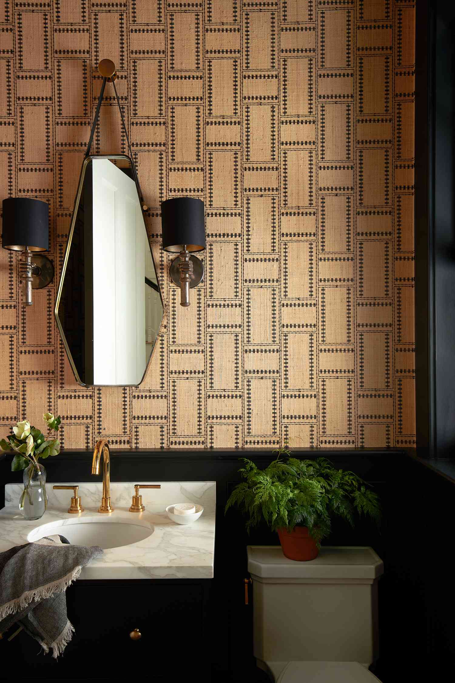 a powder bathroom with black accents and a brown printed wallpaper