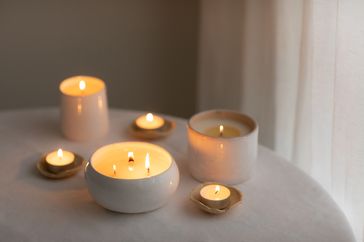 Lit candles of various shapes and sizes arranged on a table