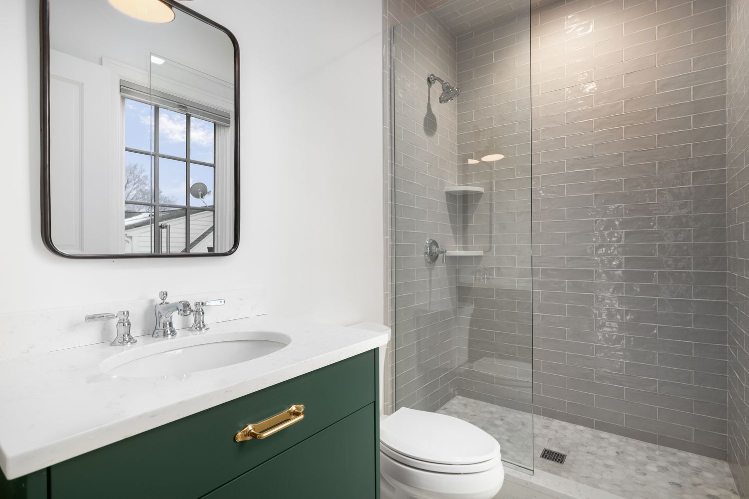 bathroom with a green vanity, white granite countertop, and a shower lined with subway and mosaic tiles