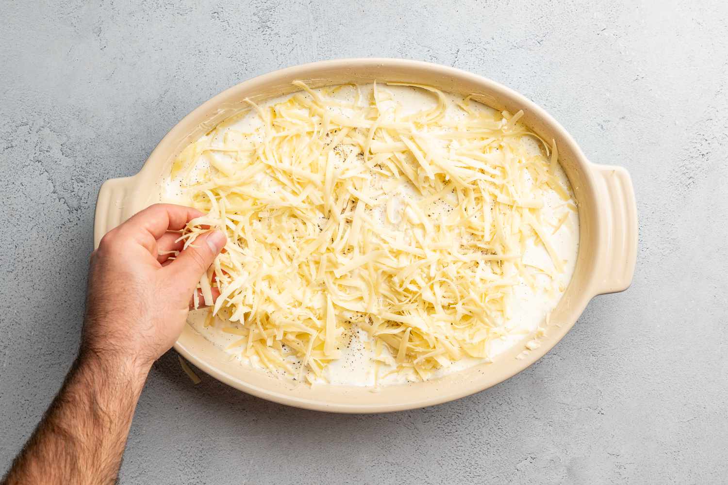 adding grated cheese to scalloped potatoes recipe