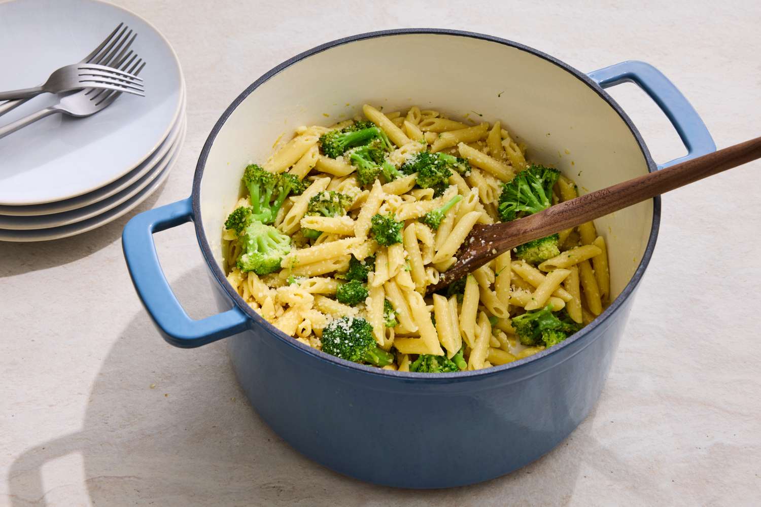 Pot filled with penne pasta and broccoli wooden spoon in the pot