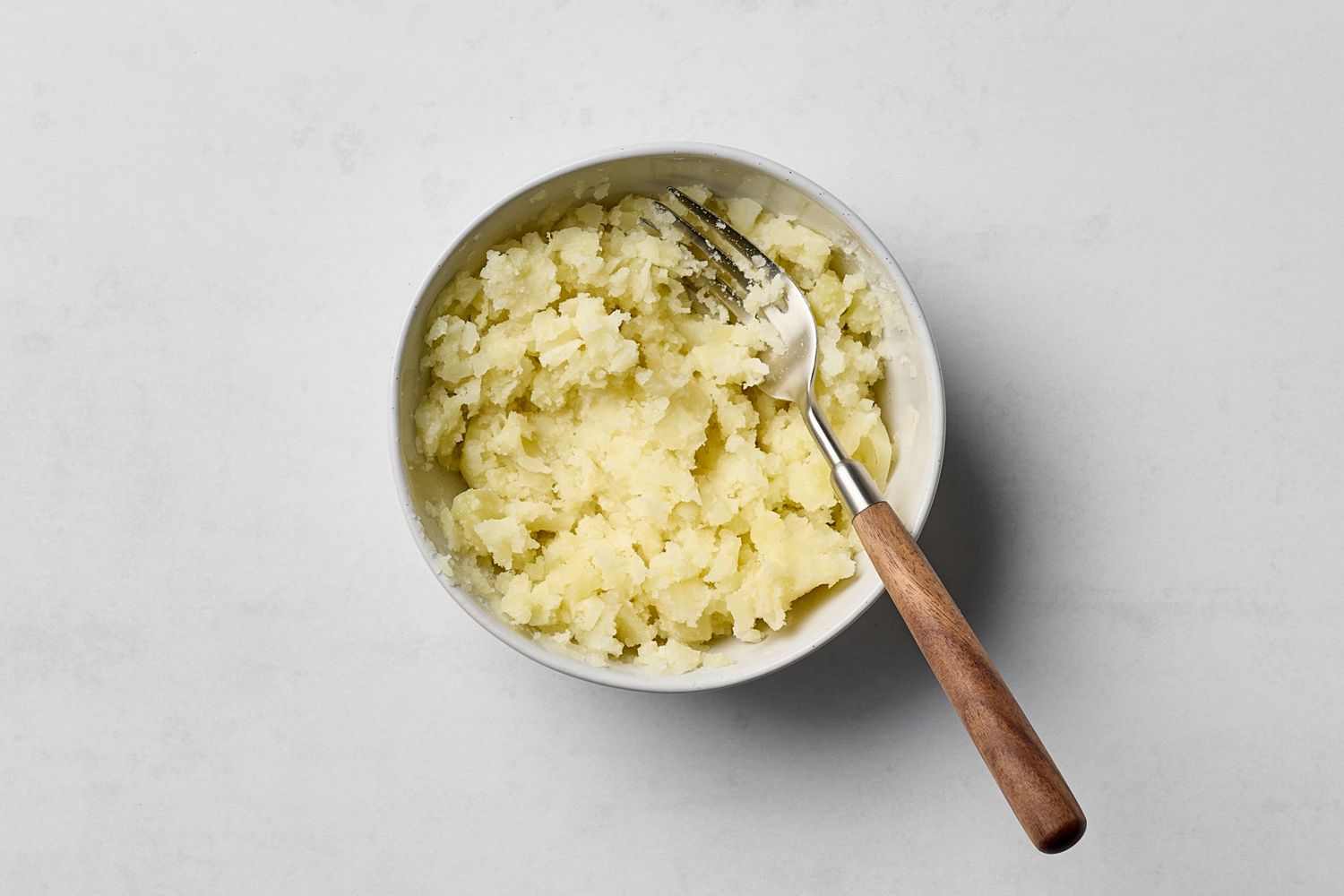 A bowl of mashed potatoes with a fork resting on the side