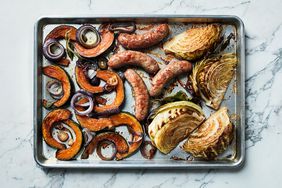 sausages cabbage vegetables on baking sheet