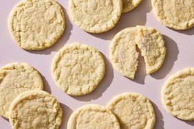 Several sugar cookies arranged on a surface one partially broken