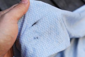 A hand holding a piece of fabric with a visible grease stain