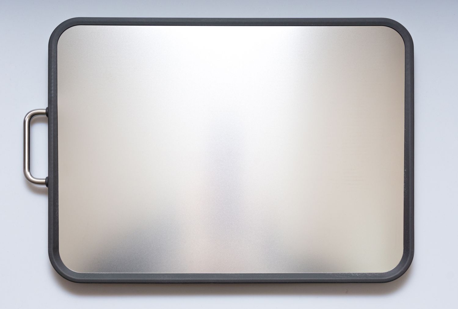 A stainless steel cutting board with a handle on the left