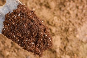 fertilizer on shovel over soil with space for text or design