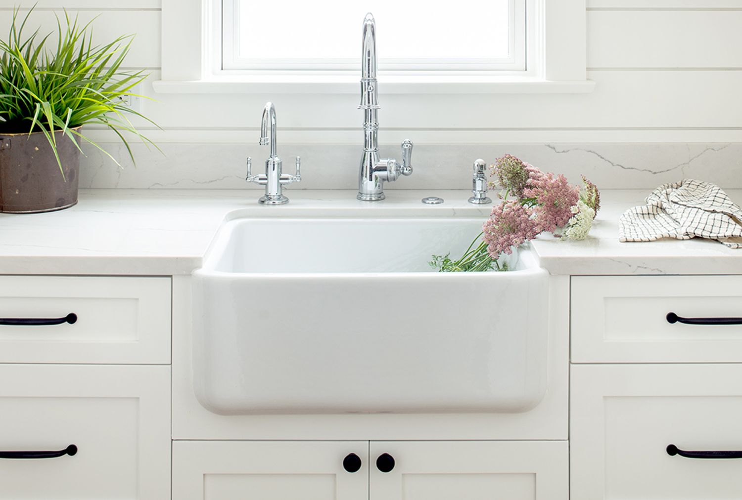 Porcelain kitchen sink with a faucet countertop with flowers and nearby cabinetry