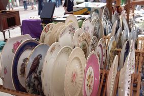 A display of decorative plates on a wooden rack at a market stall