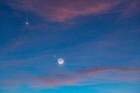 Night sky featuring the crescent moon and visible planets surrounded by soft clouds
