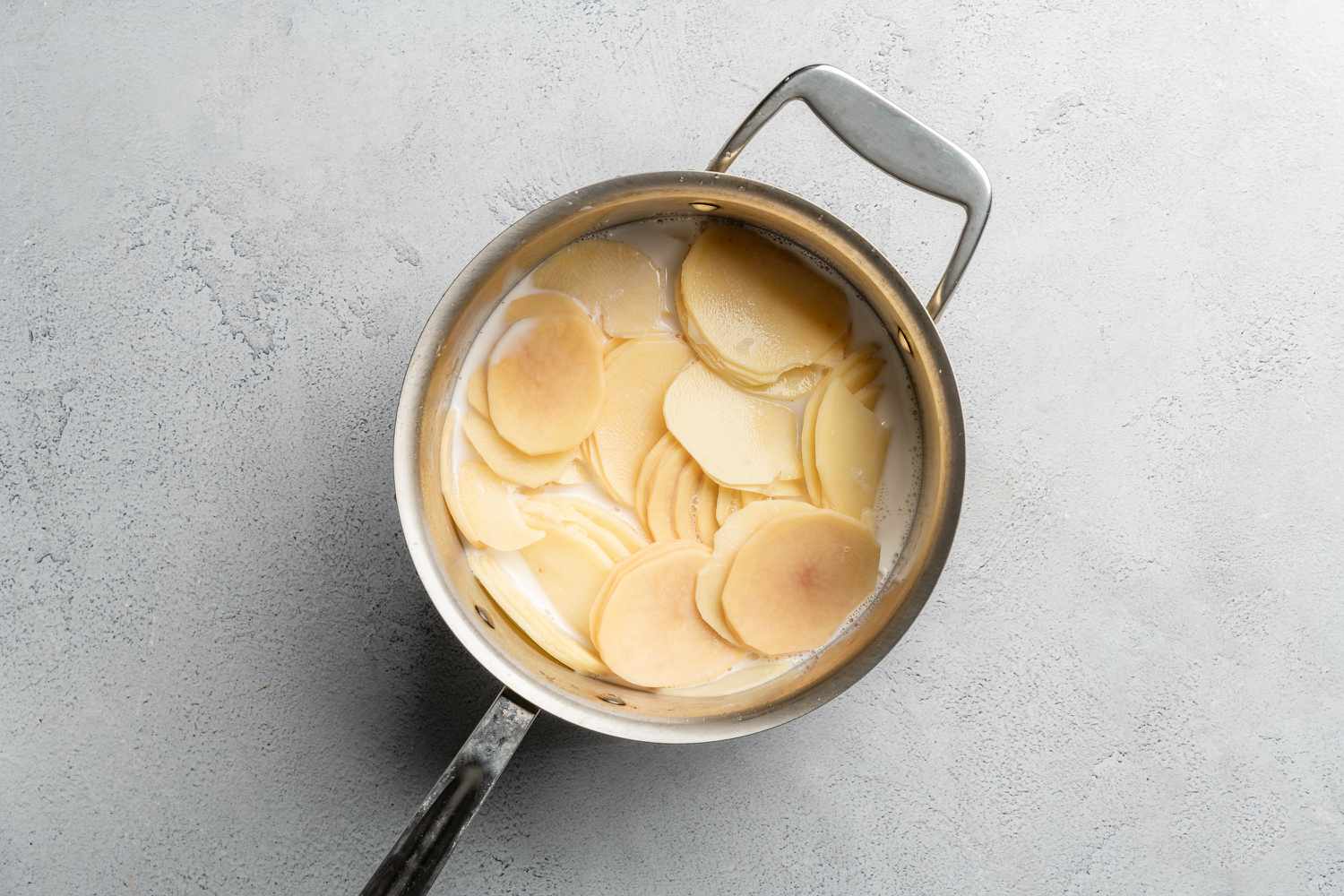 sliced potatoes in pan of milk
