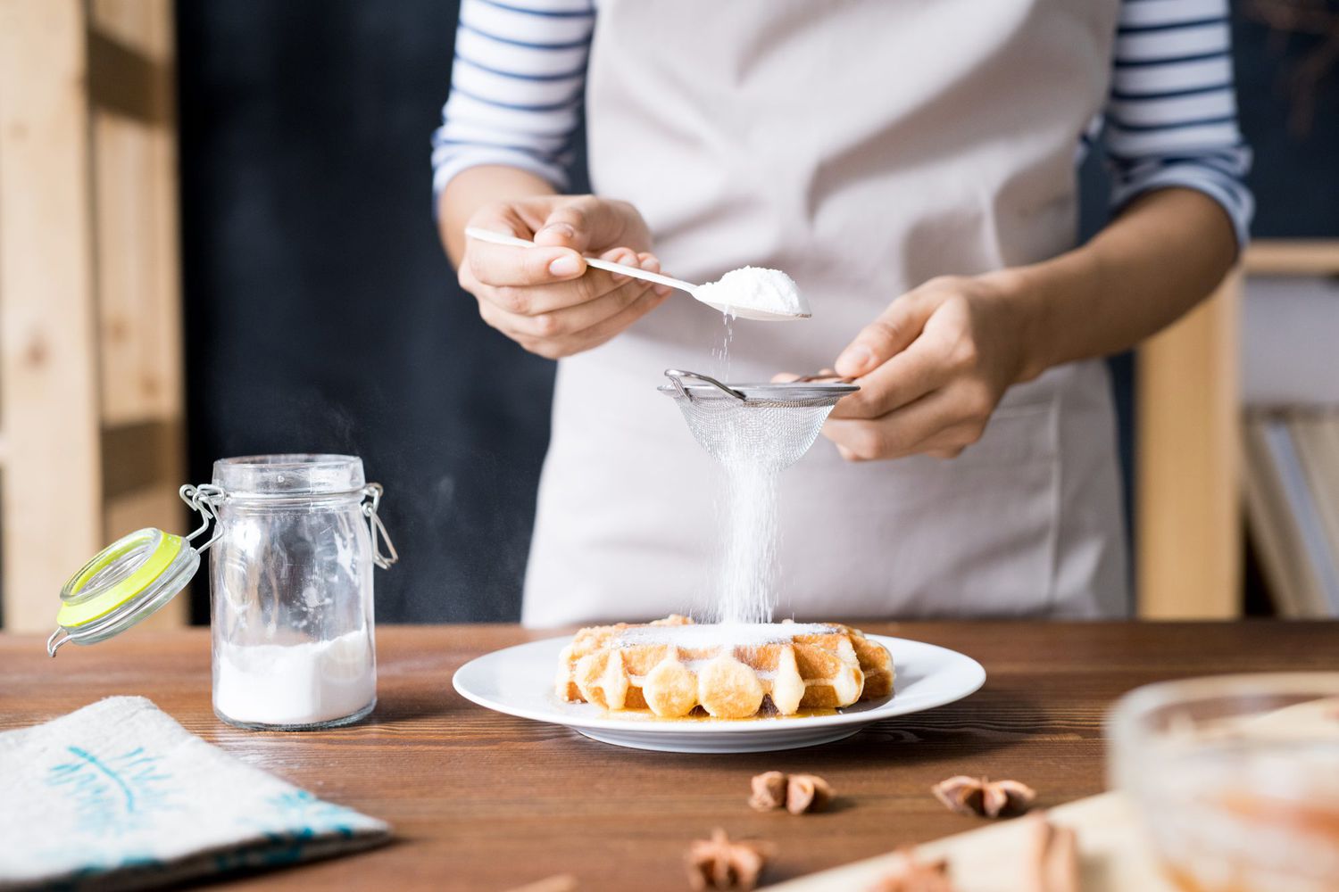 Woman sifting powdered sugar over waffles
