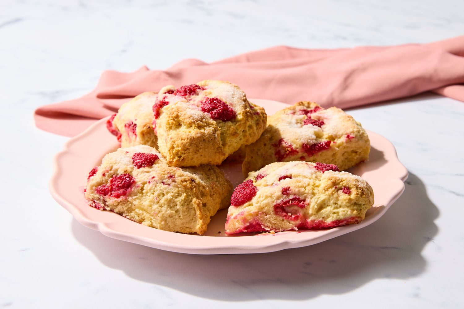 Plate of raspberry scones with a pink cloth in the background