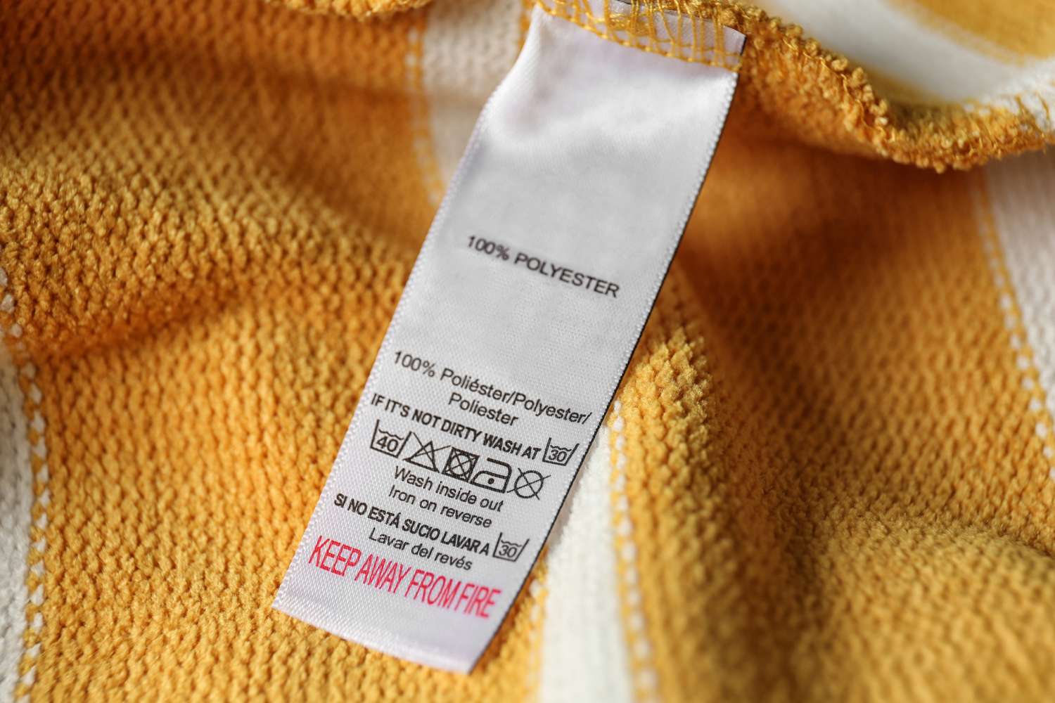 A detailed clothing care label attached to a yellow textile fabric